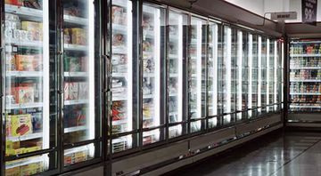 A row of refrigerators in a grocery store filled with food.