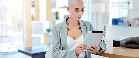 A bald woman is holding a tablet and a piece of paper.