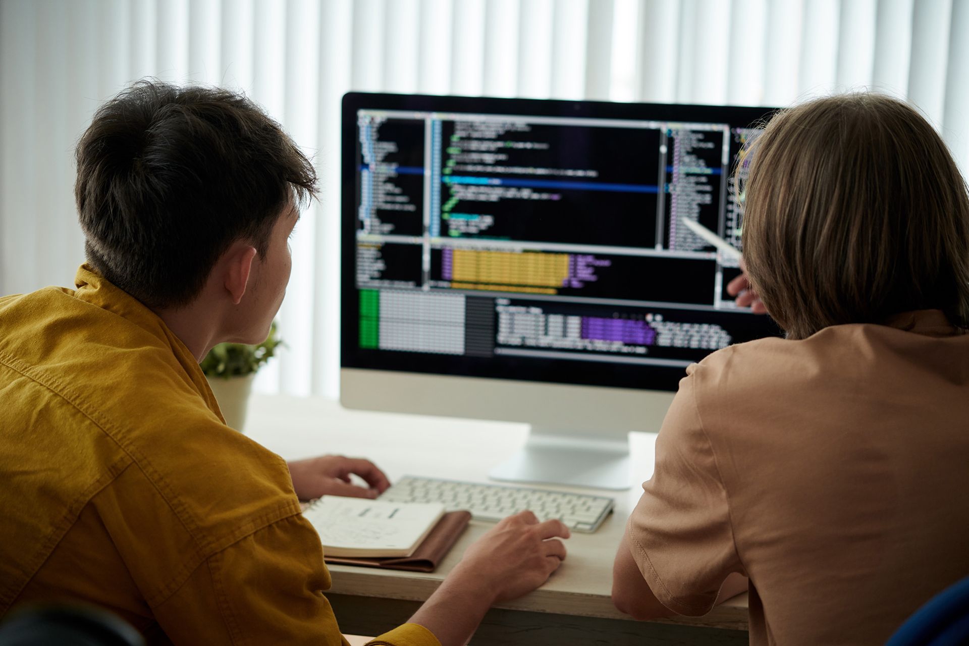 A man and a woman are looking at a computer screen.