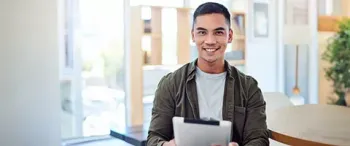 A man is holding a tablet in his hands and smiling.