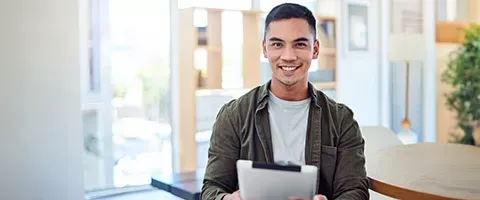 A man is holding a tablet in his hands and smiling.