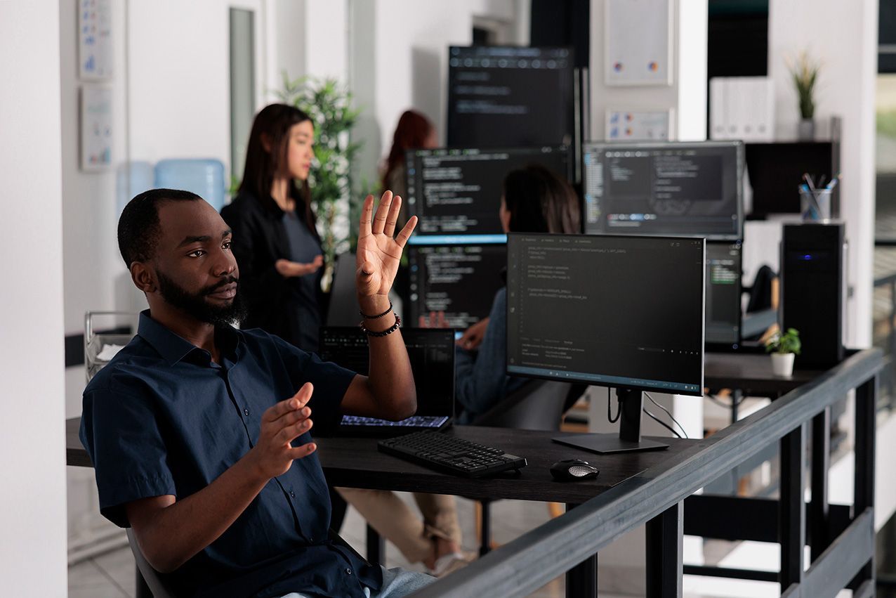 A man is sitting at a desk in front of a computer in an office.