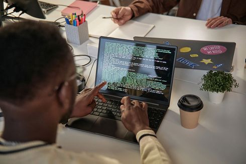 A man is sitting at a table using a laptop computer.