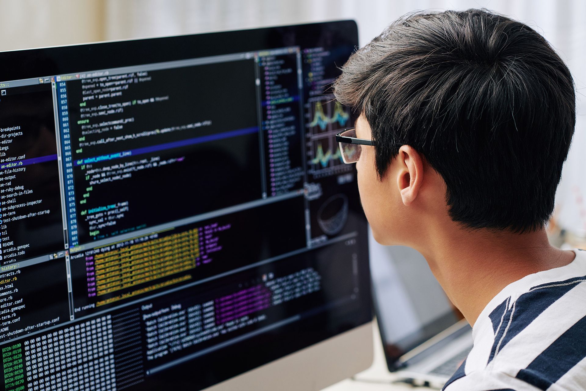 A man wearing glasses is looking at a computer screen.