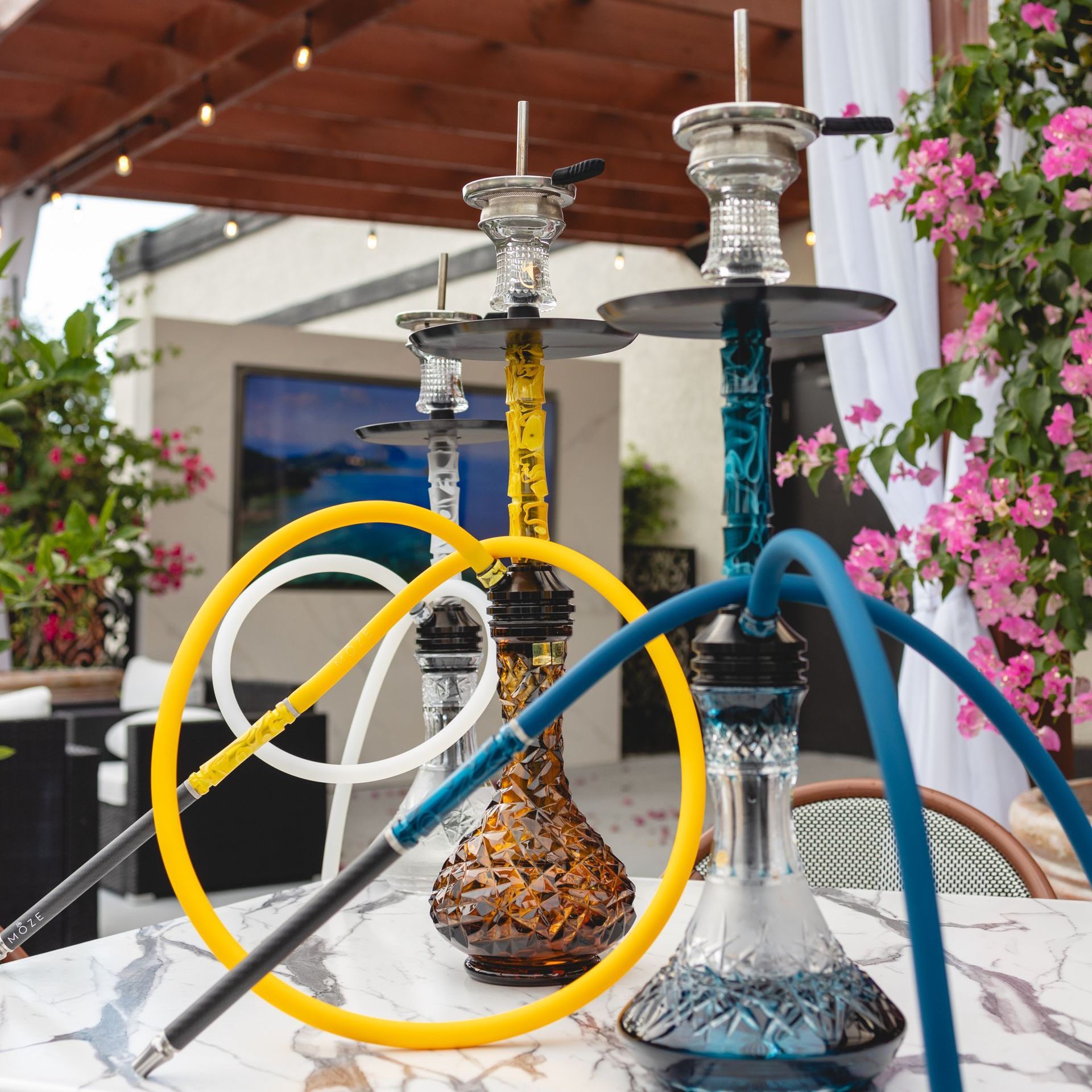 Two hookahs are sitting on a table with flowers in the background