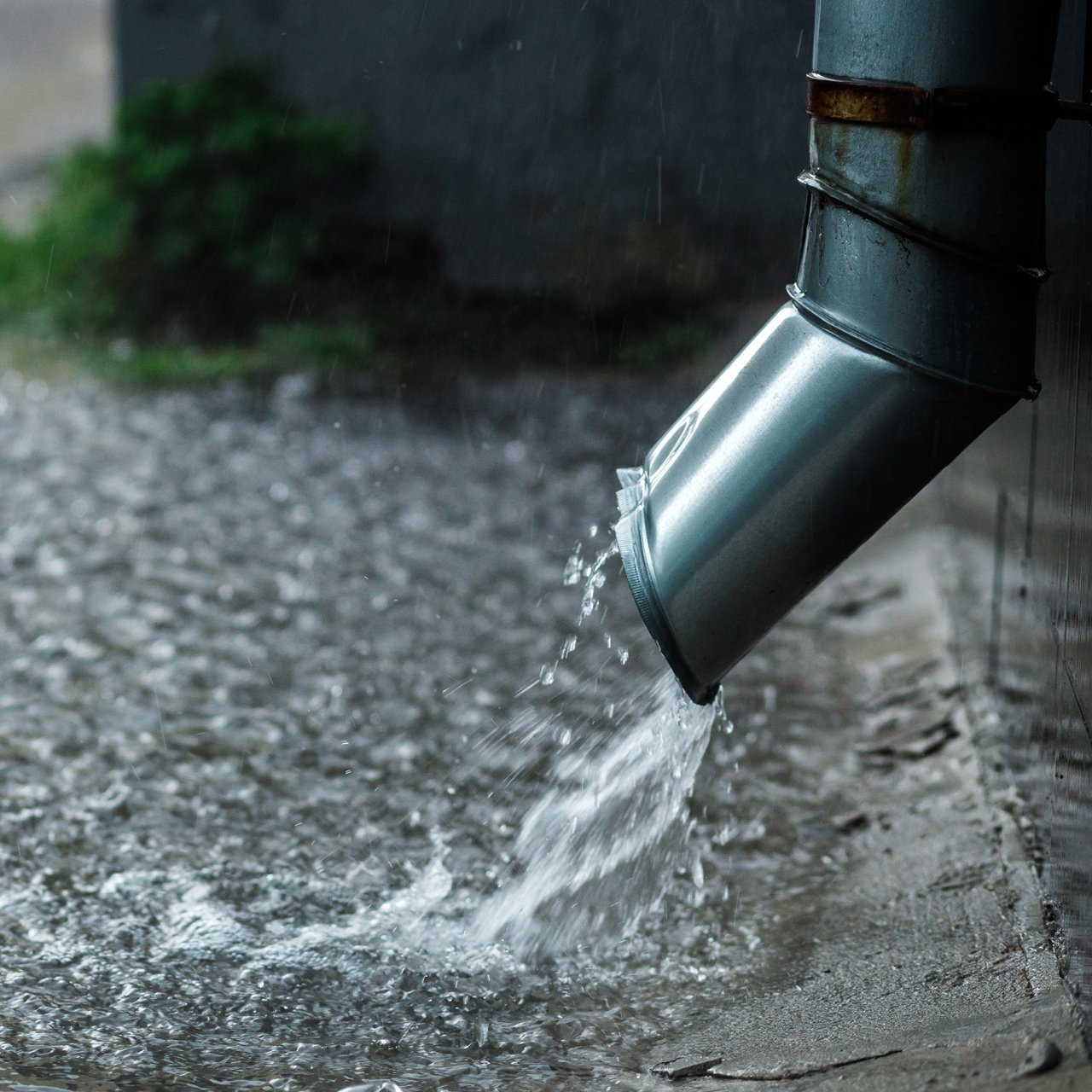 Water is coming out of a metal pipe in the rain