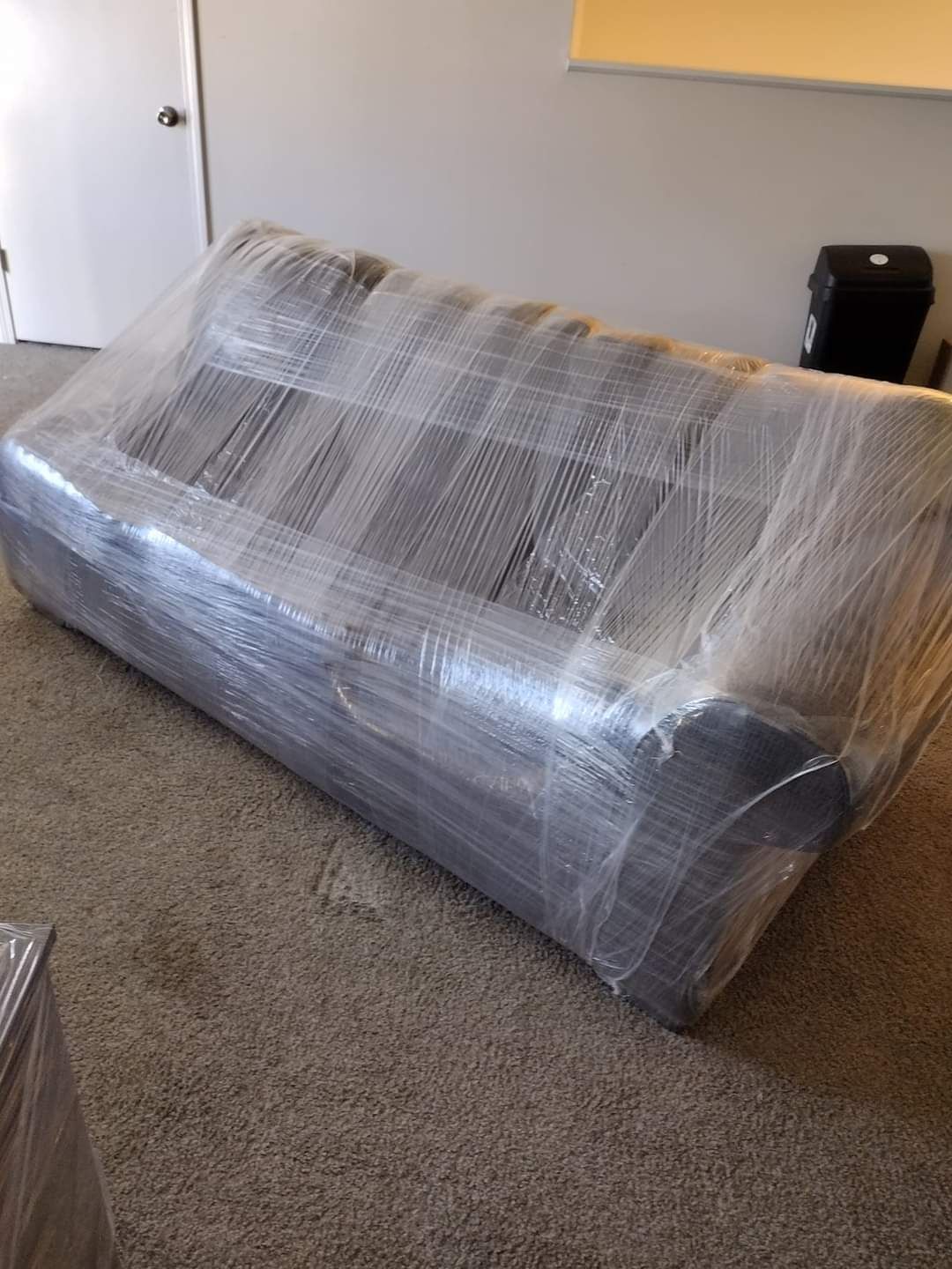 Large gray wrapped sofa on a carpeted floor in a room