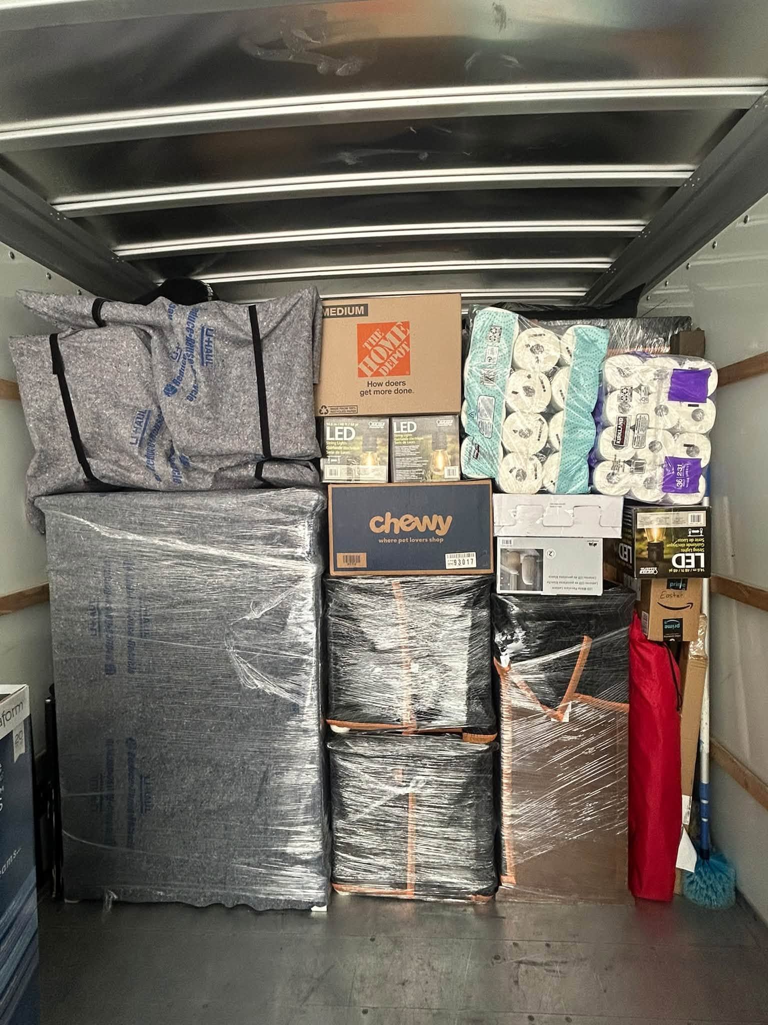 Packed storage unit filled with stacked boxes and wrapped items, including bedding and household goods.
