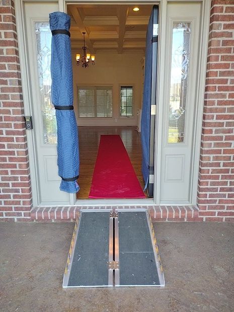 Front entrance with a red carpet leading inside and a wheelchair ramp over the threshold.