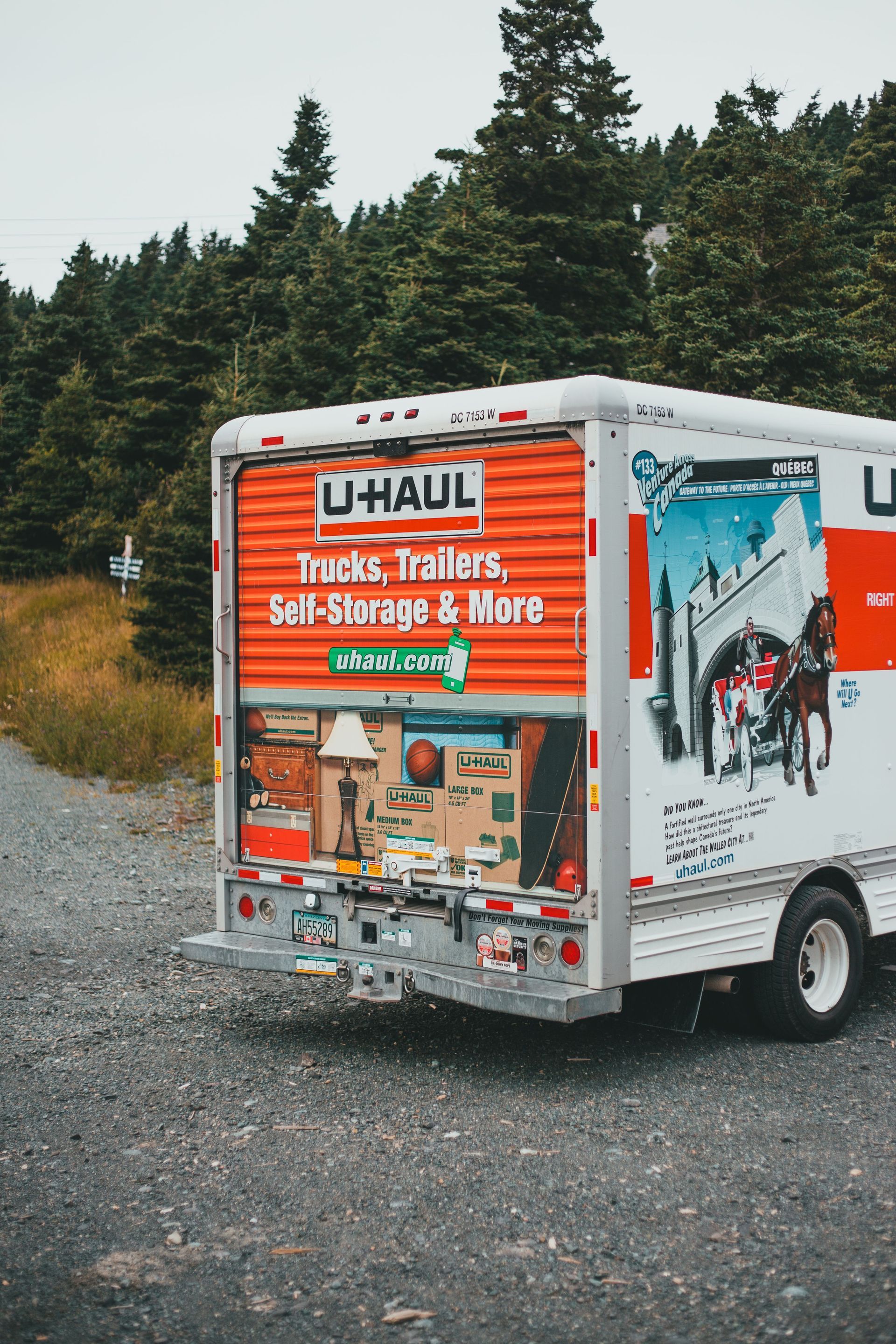 U-Haul moving truck parked on gravel beside a forest, rear doors and side branding visible