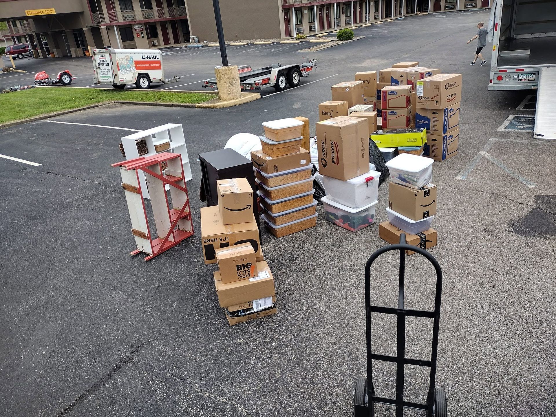 Stacks of cardboard boxes and packing supplies in a parking lot beside a truck loading area.