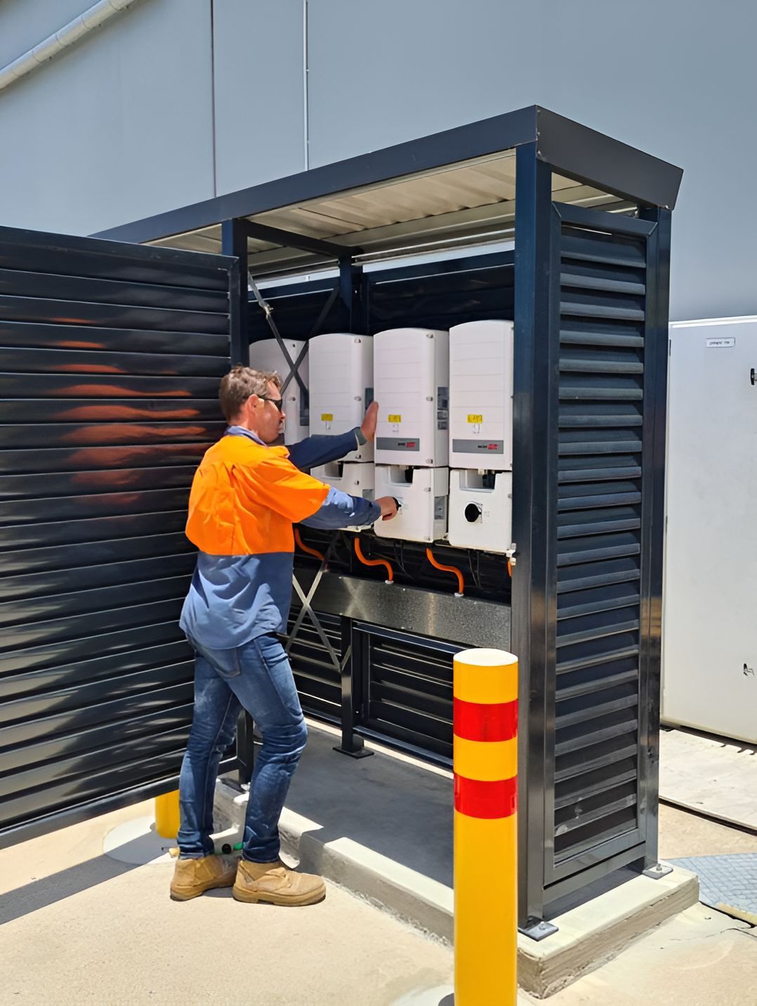 A Man In An Orange Shirt Is Working On A Solar Panel — Waltlec Industries In Garbutt, QLD