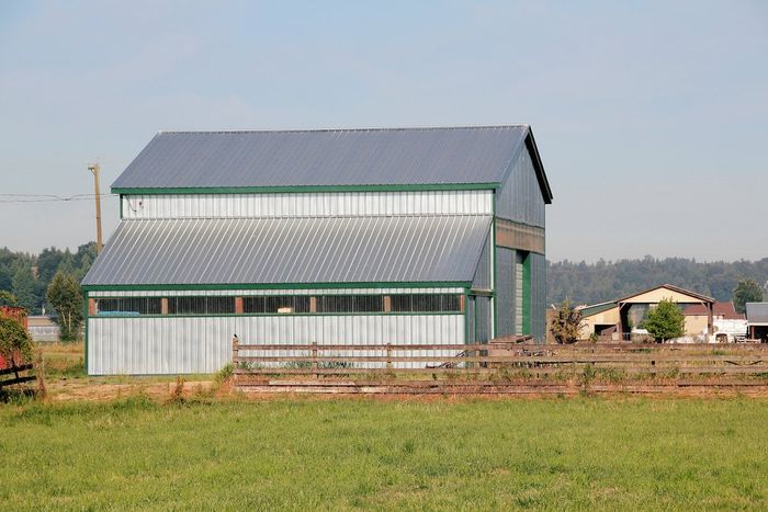 A barn is sitting in the middle of a grassy field.