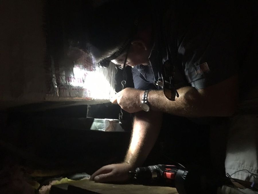 Person inspecting a dark space with a flashlight.