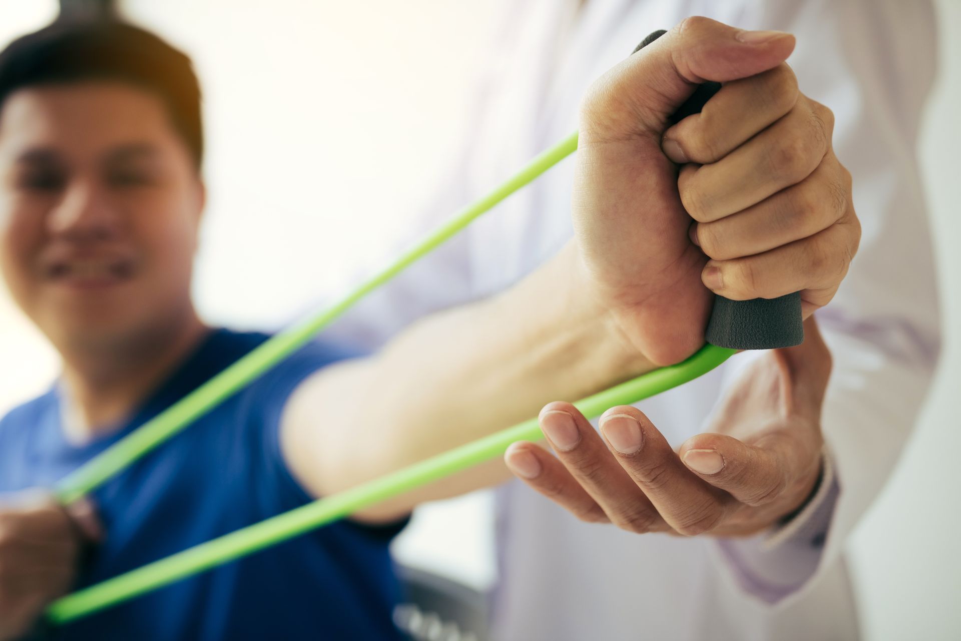 Physical therapy exercise with resistance band held by trainer and client Physical therapy exercise with resistance band held by trainer and client