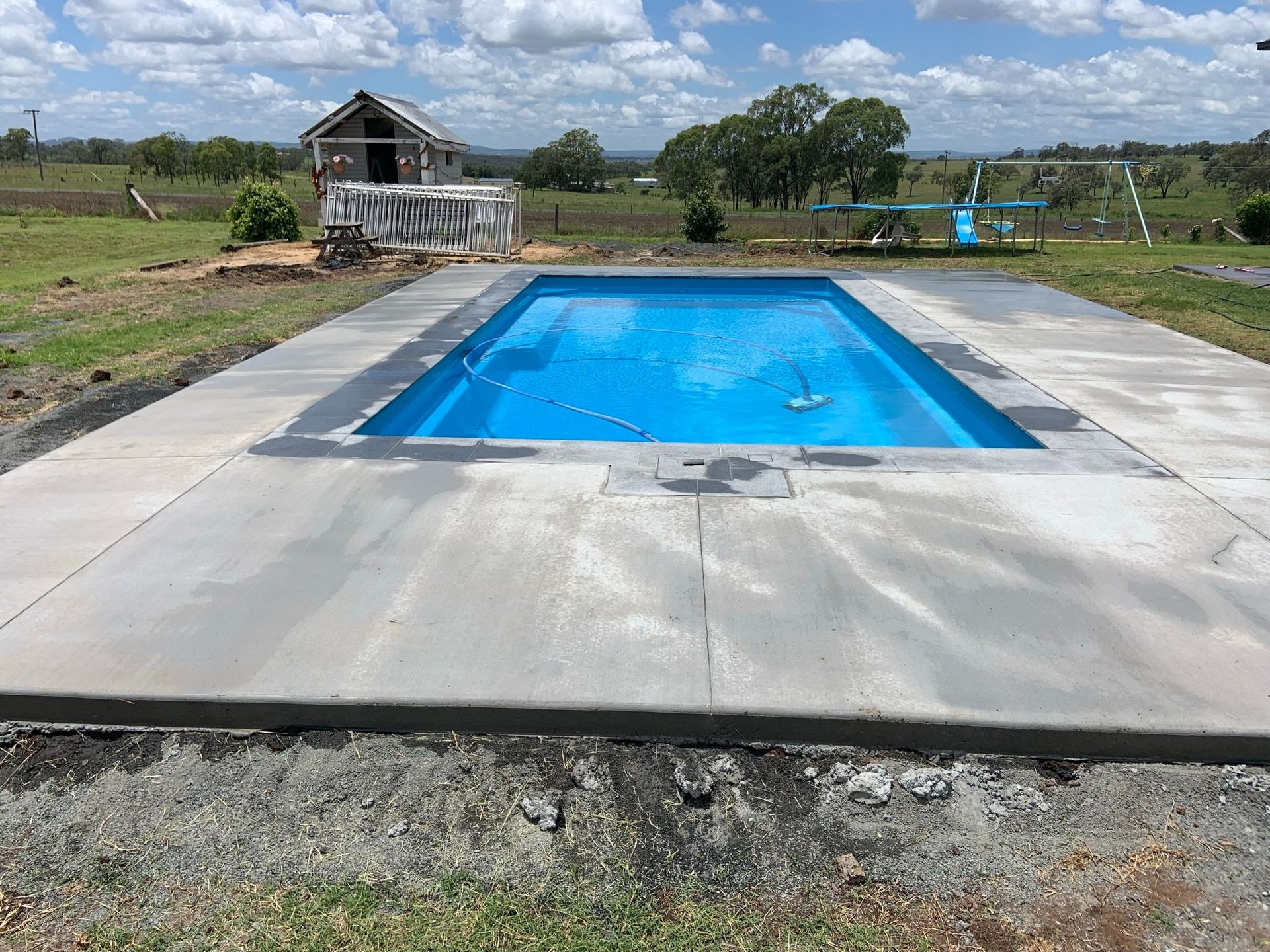 A Large Swimming Pool is Sitting on Top of a Concrete Patio — Pedro's Concreting in Pittsworth, QLD