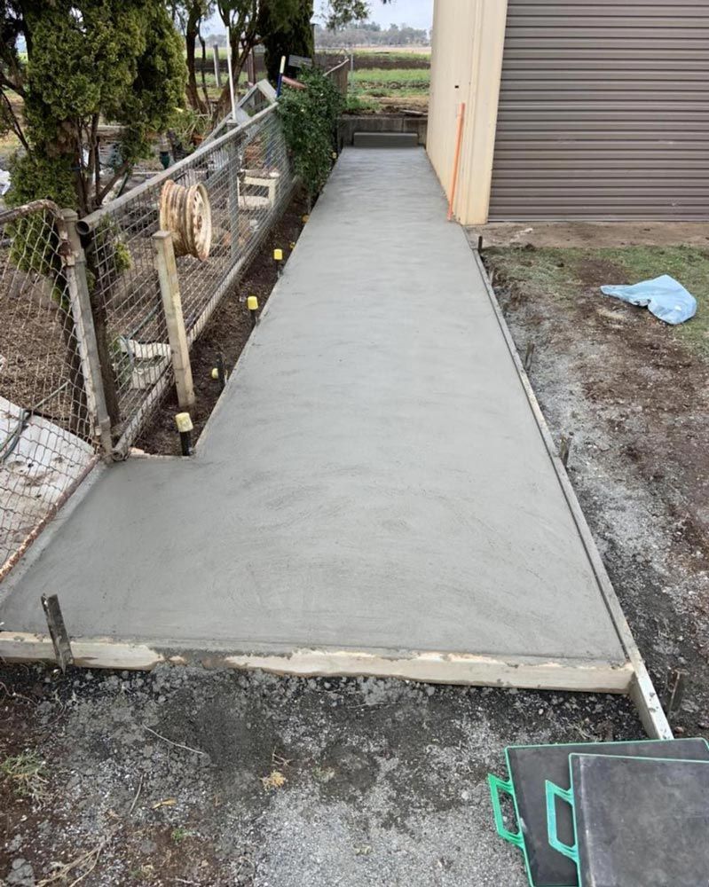 A Concrete Walkway is Being Built Next to a Fence and a Garage — Pedro's Concreting in Pittsworth, QLD