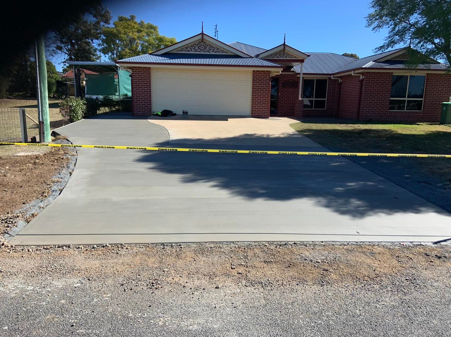 A Brick House With a Concrete Driveway in Front of It — Pedro's Concreting in Pittsworth, QLD