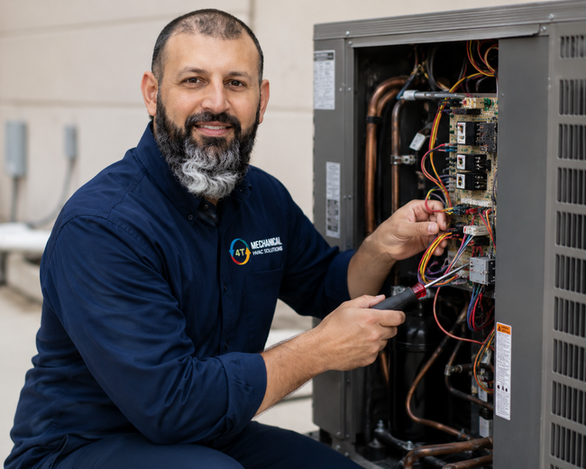 Technician in a navy shirt repairs wiring inside an open electrical cabinet with tools.