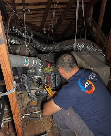 Technician inspecting HVAC equipment in an attic crawlspace, surrounded by ducts and exposed beams