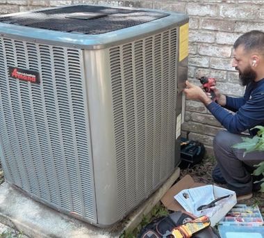 Technician repairing outdoor air conditioner unit with tools beside a brick wall