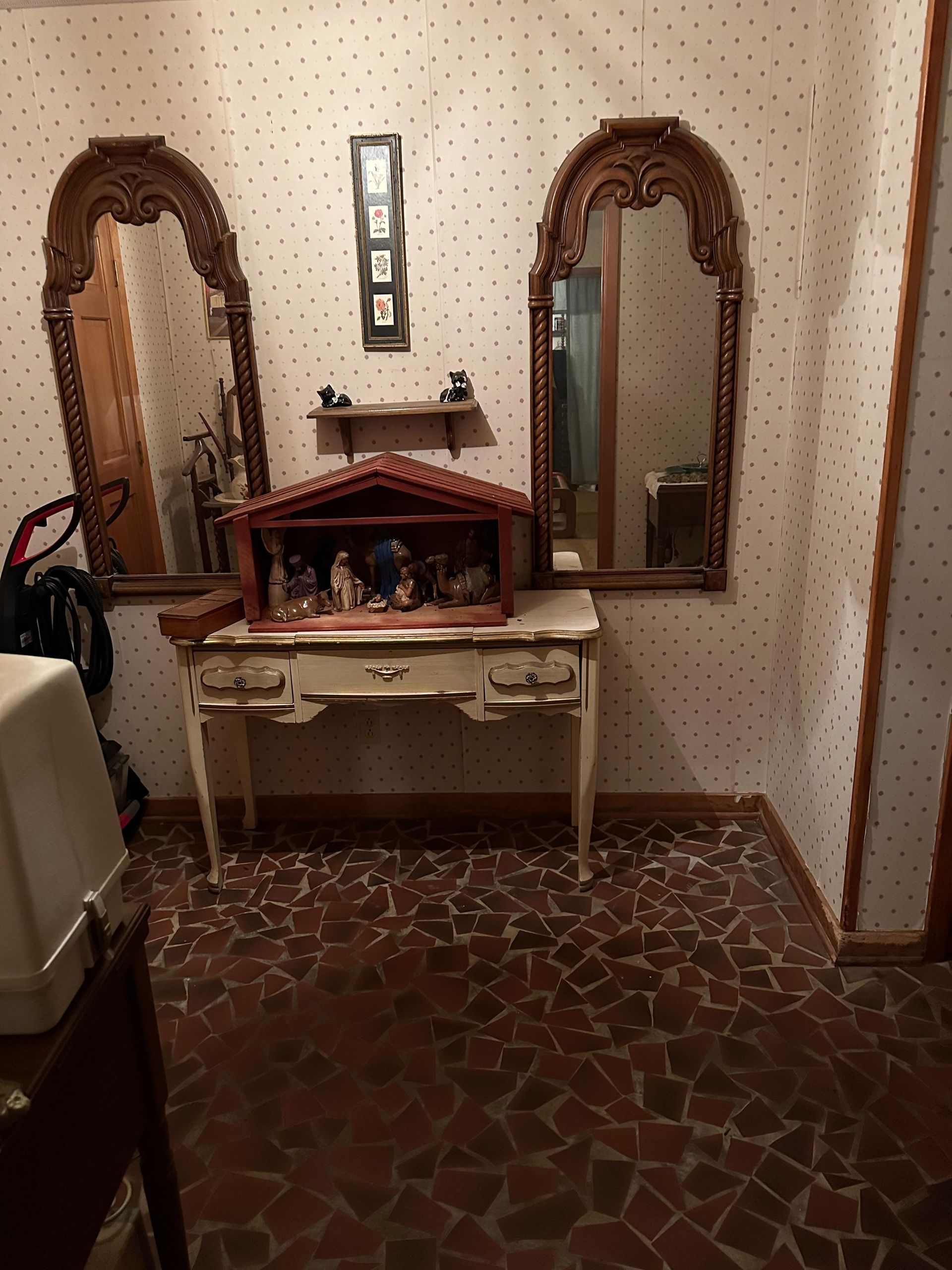 A room with a nativity scene on a table and two mirrors.