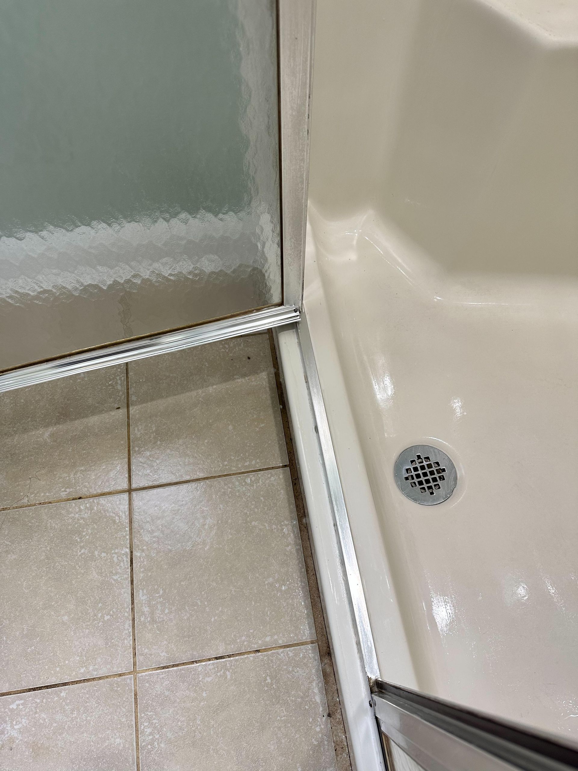 A bathroom with a shower stall and a drain on the floor.