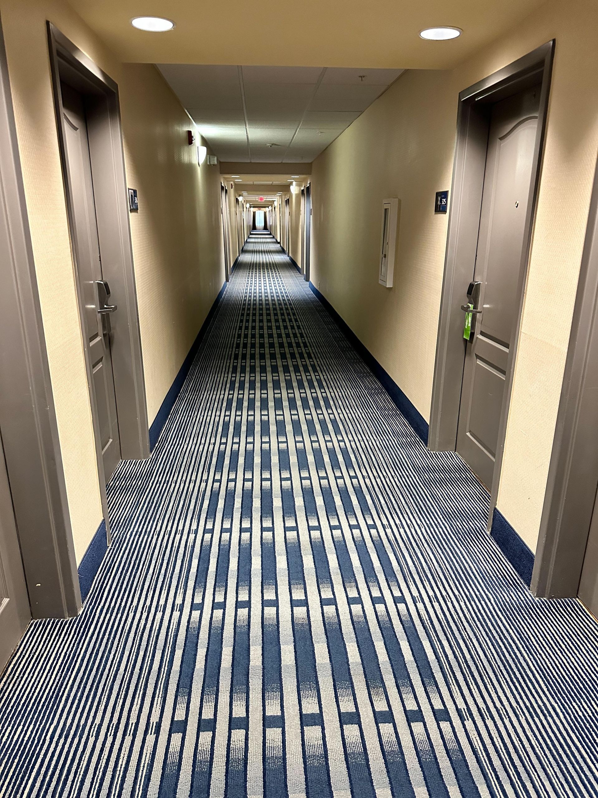 A long hallway in a hotel with a blue and white striped carpet.