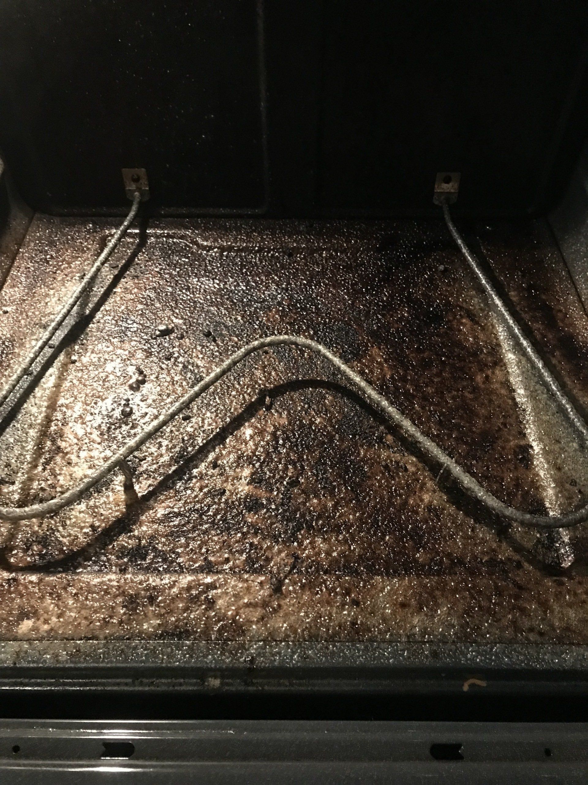 A very dirty oven with a few wires sticking out of it