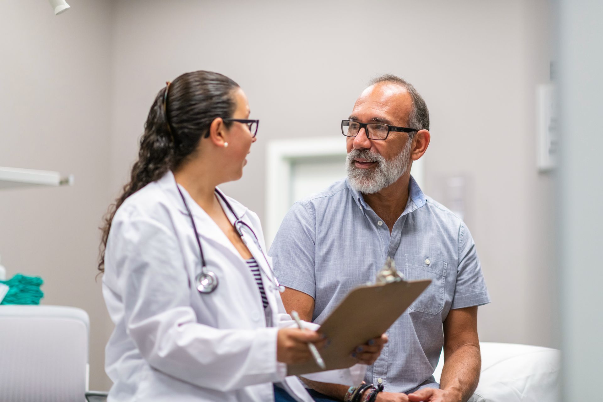 A doctor is talking to a patient while holding a clipboard.