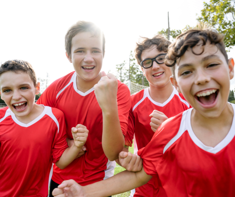 A group of young boys in red jerseys are standing next to each other on a field.