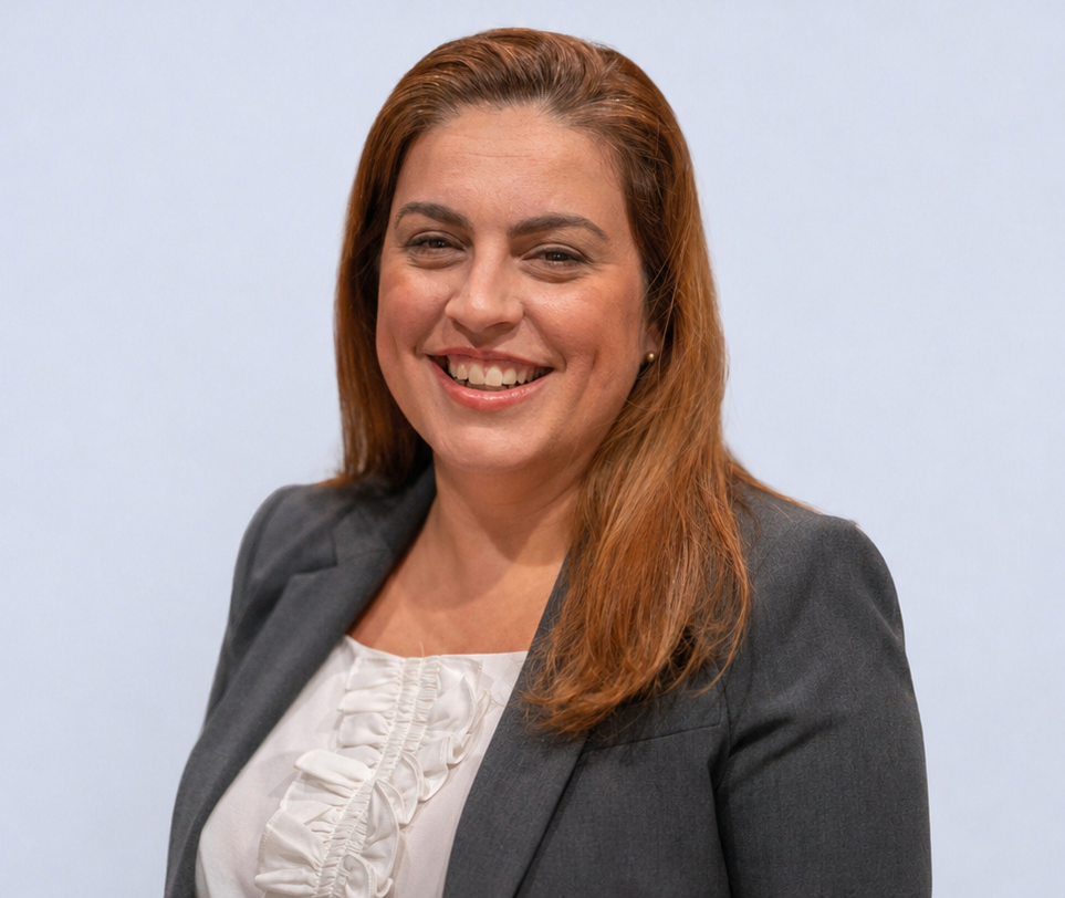 Smiling woman in a gray blazer against a blurred gray background