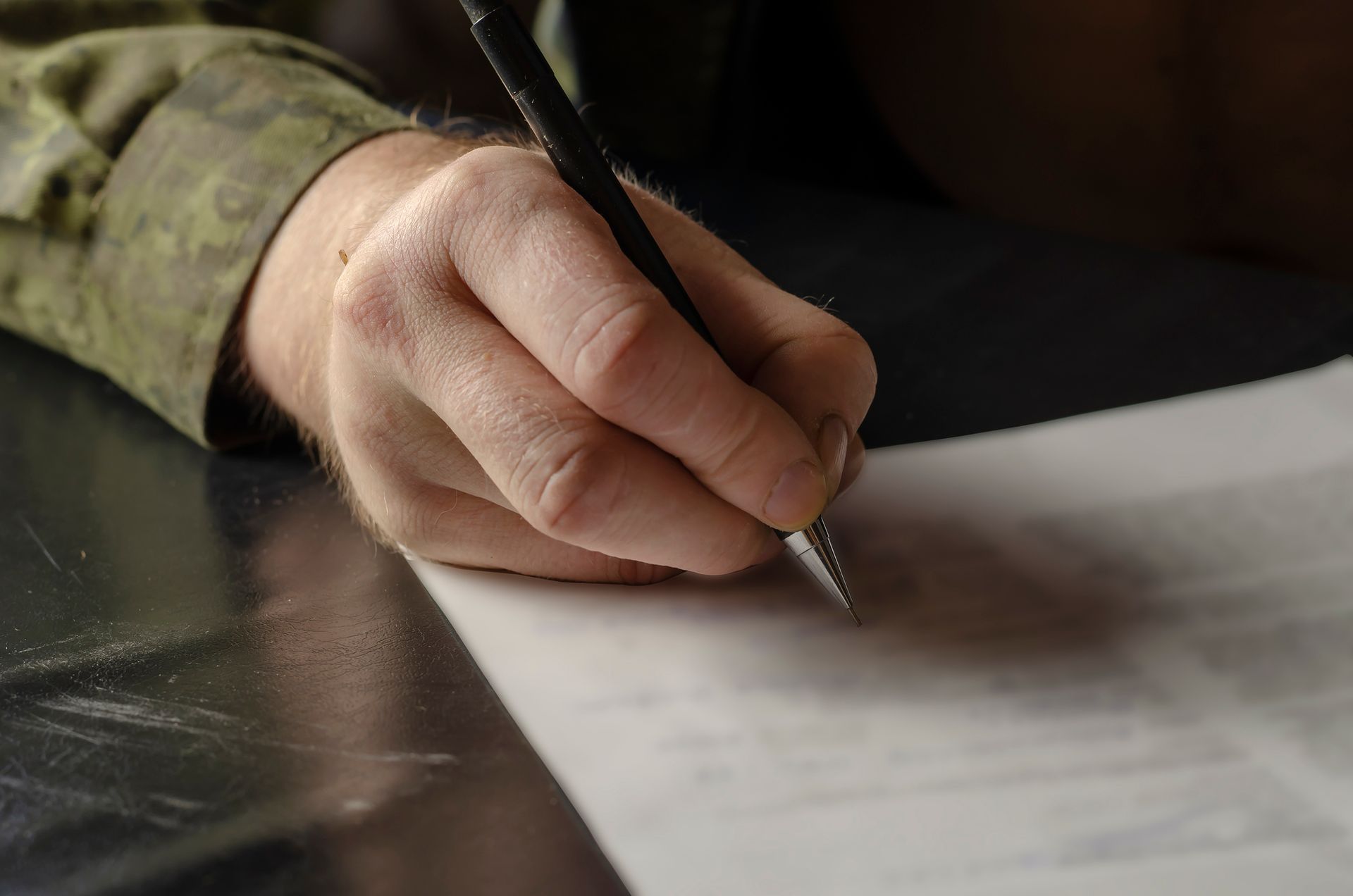 Hand writing on paper with a pen at a table