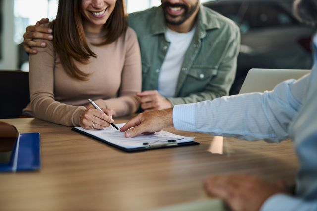 Two people reviewing a document and signing papers at a table in an office