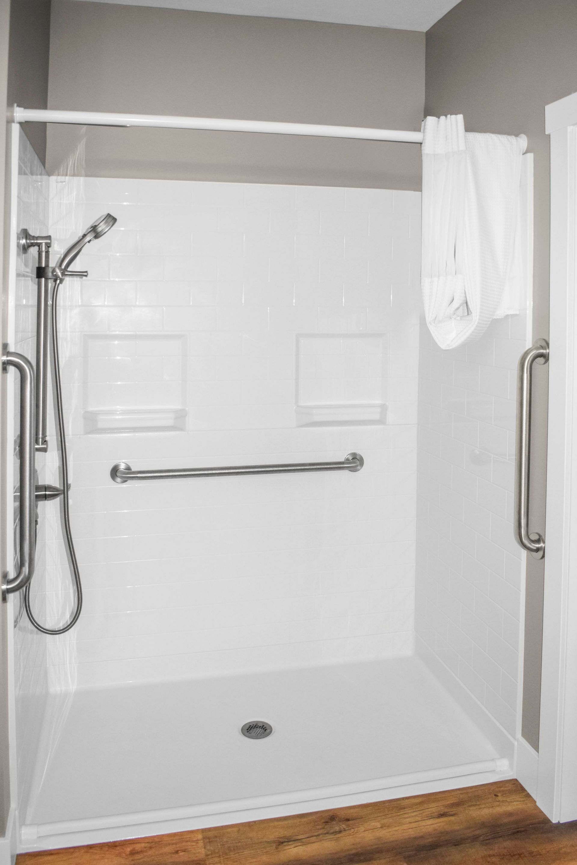 A walk-in shower with the curtain hanging from the curtain rod.