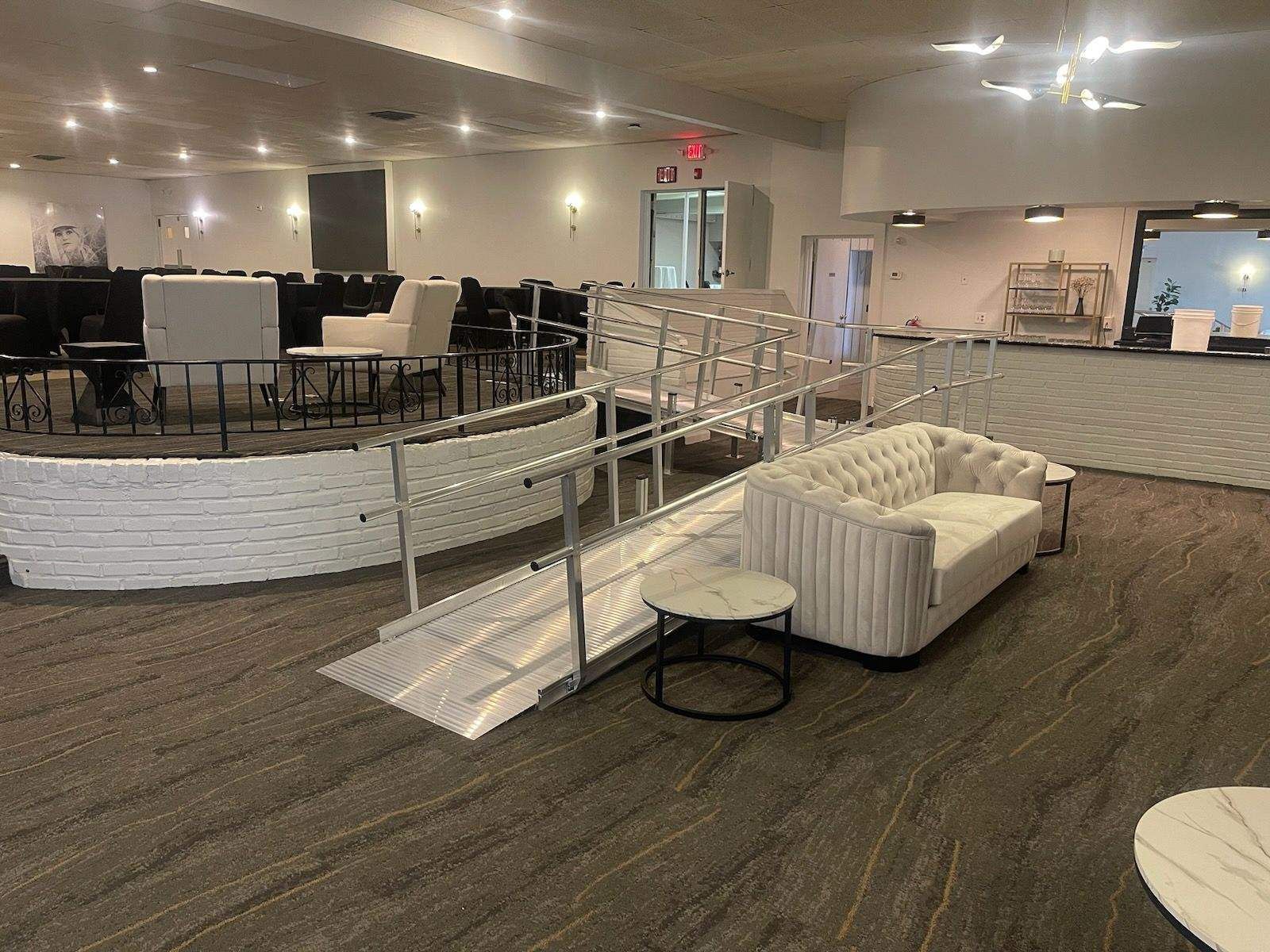 A large room with a couch, chairs, tables, and a wheelchair ramp.