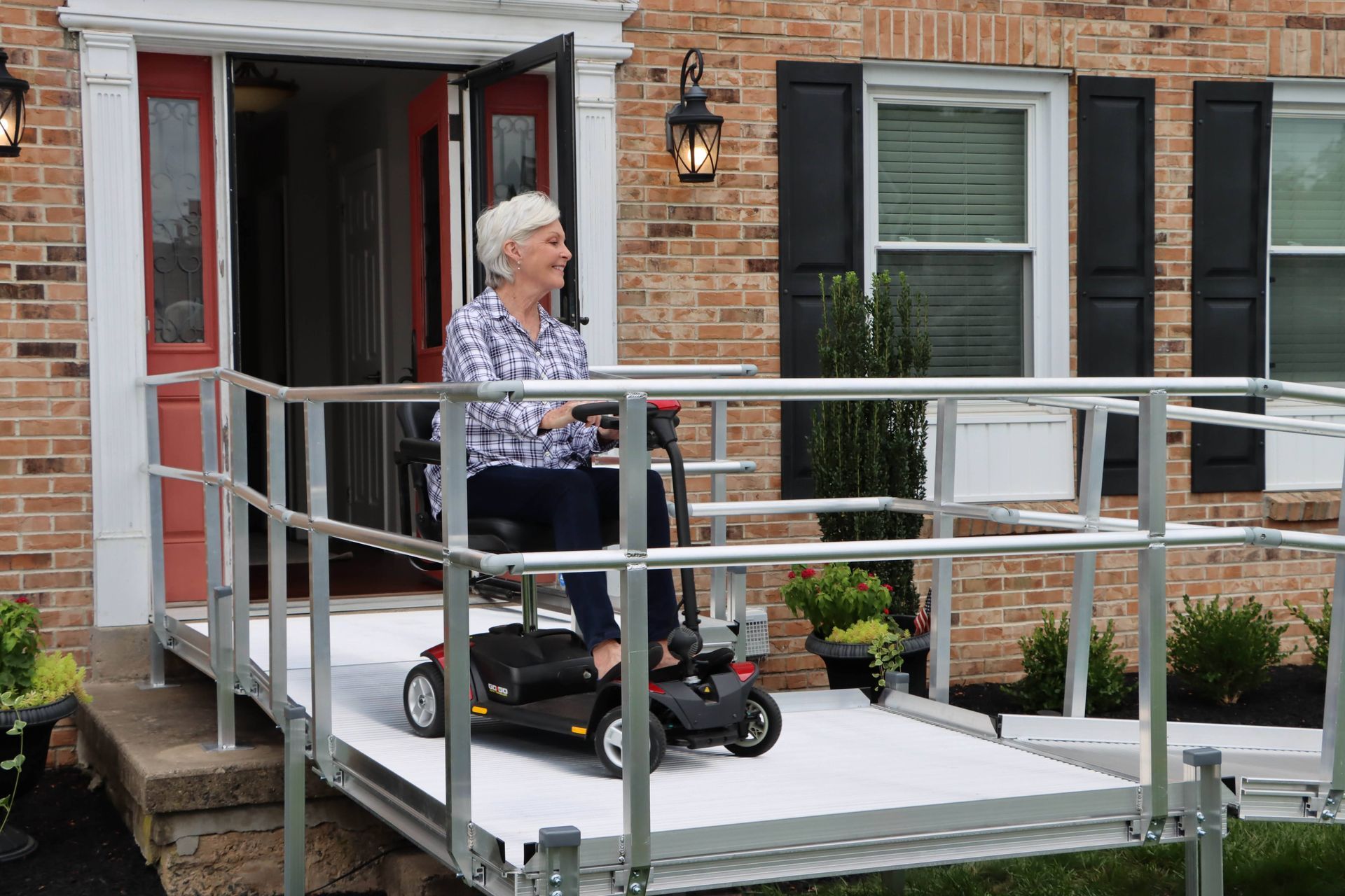 Woman on a mobility scooter on a house porch with a wheelchair ramp.