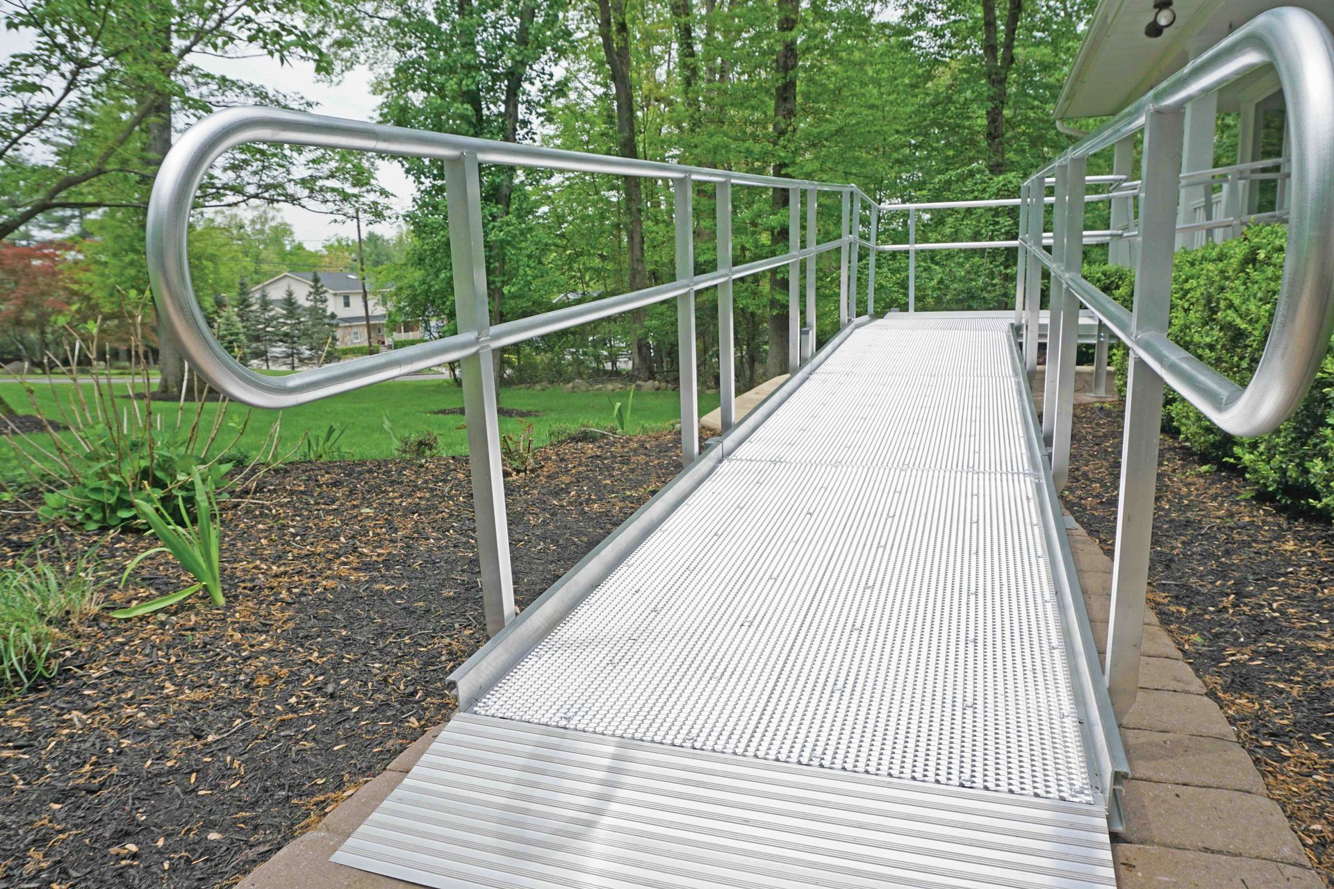 Metal accessibility ramp with handrails in a wooded park setting