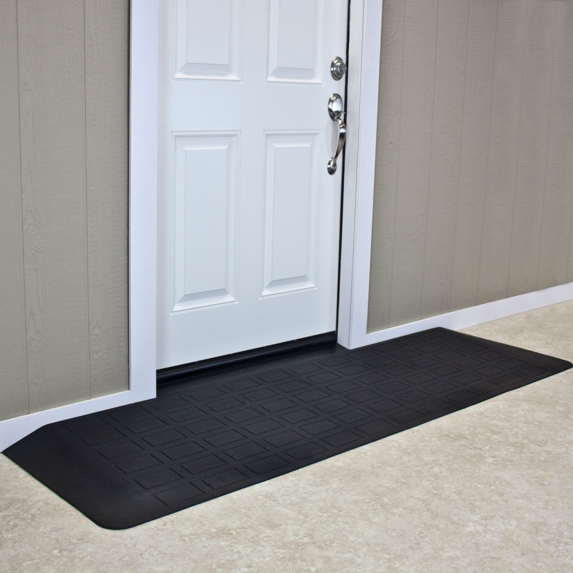 A black mat is sitting in front of a white door.