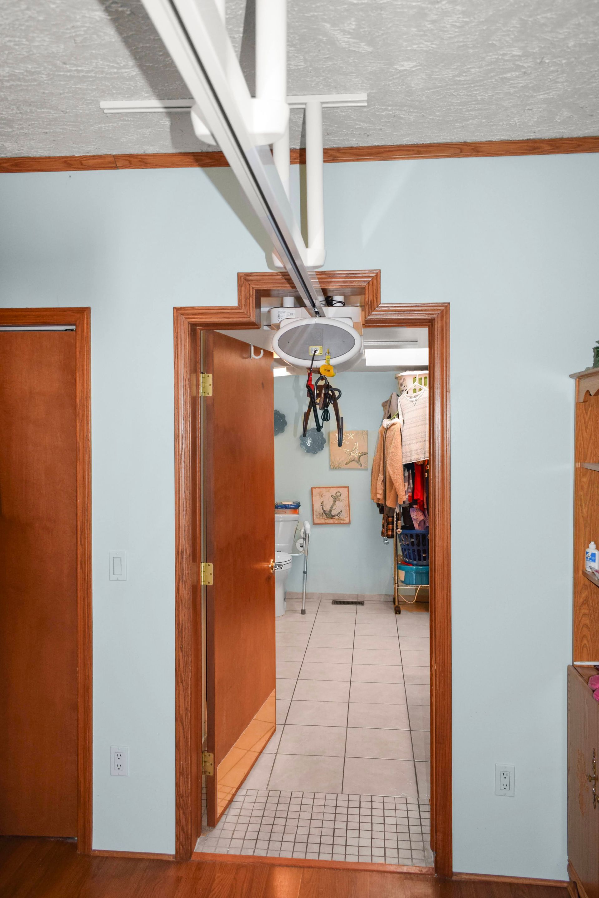 Hallway with a ceiling lift over the doorway. Doorway is brown, walls are blue.