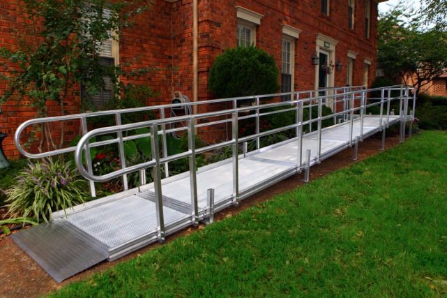 A handicapped ramp is sitting in front of a brick building.