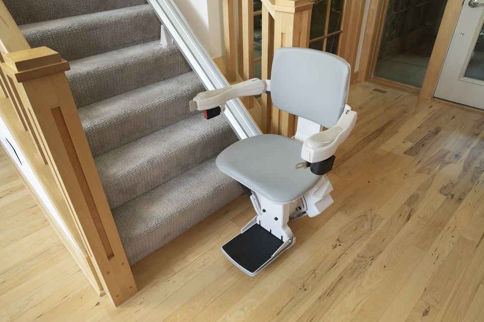 A stair lift is sitting on a wooden floor next to a set of stairs.
