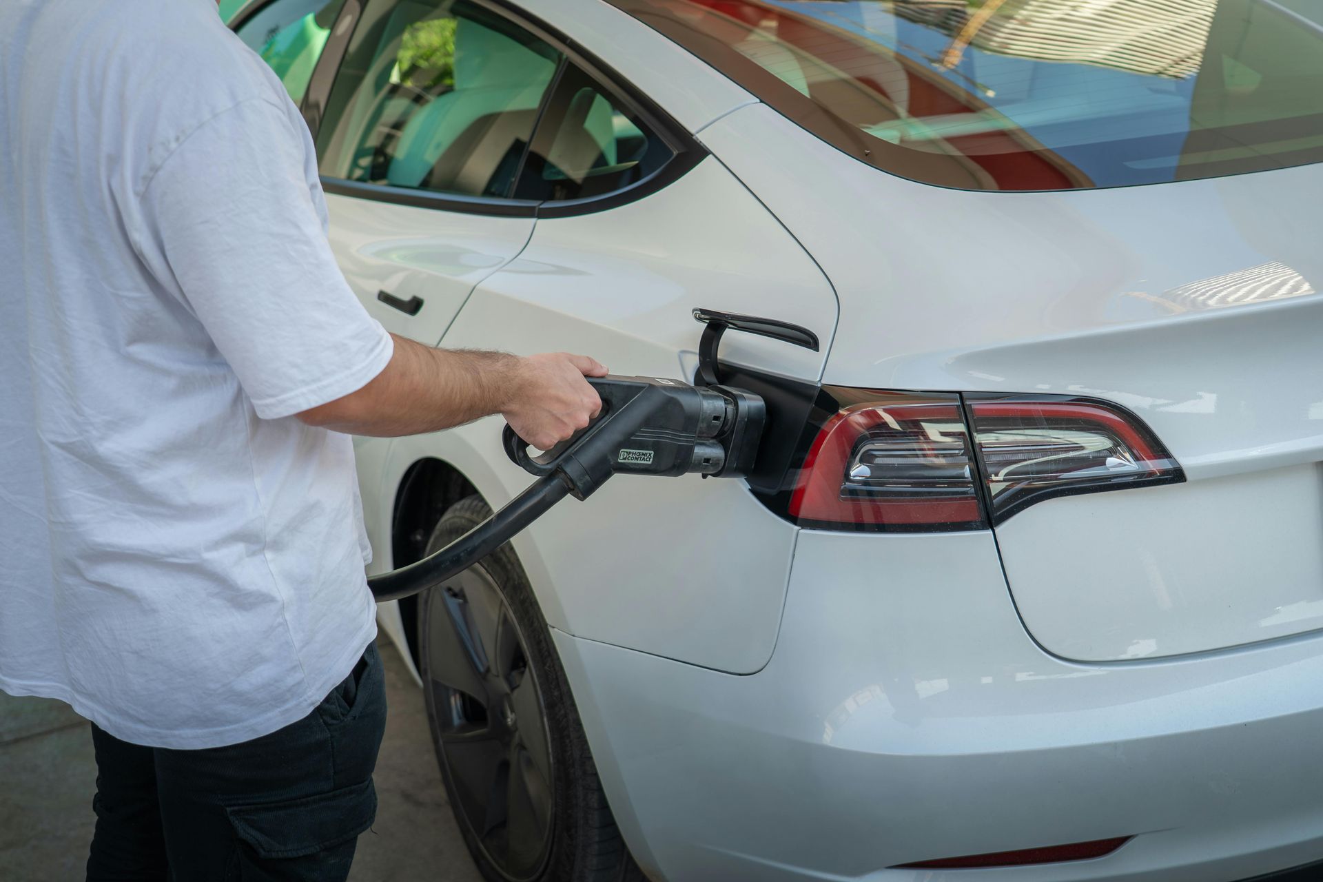 Person charging a white electric car at a station