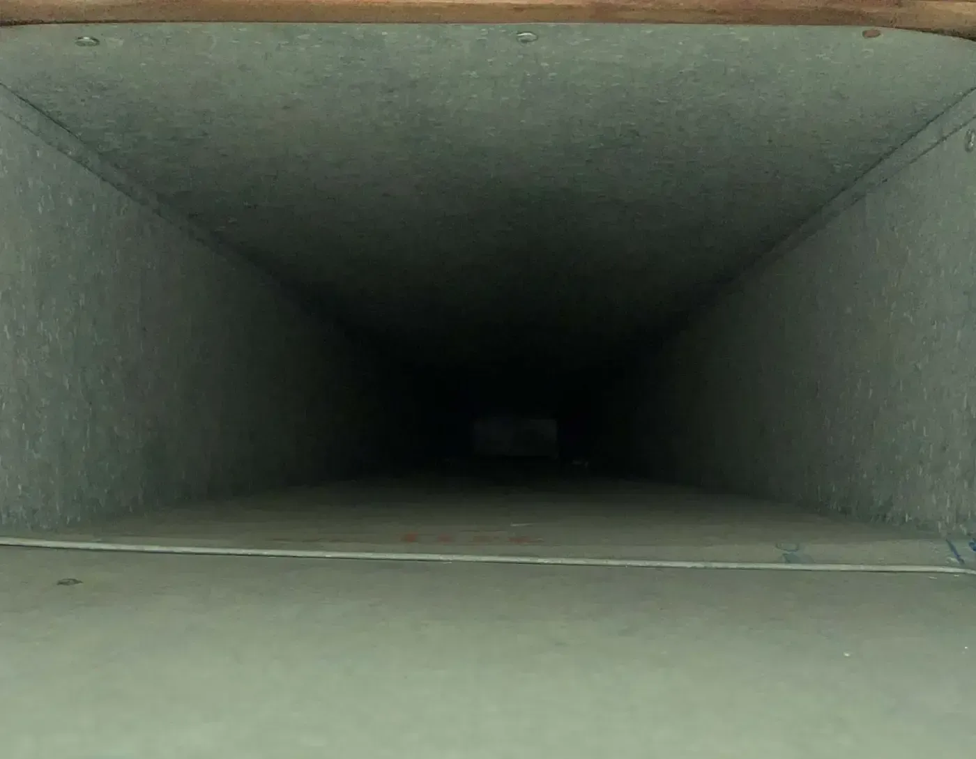 Empty rectangular ventilation duct, dark interior, light gray metal walls.