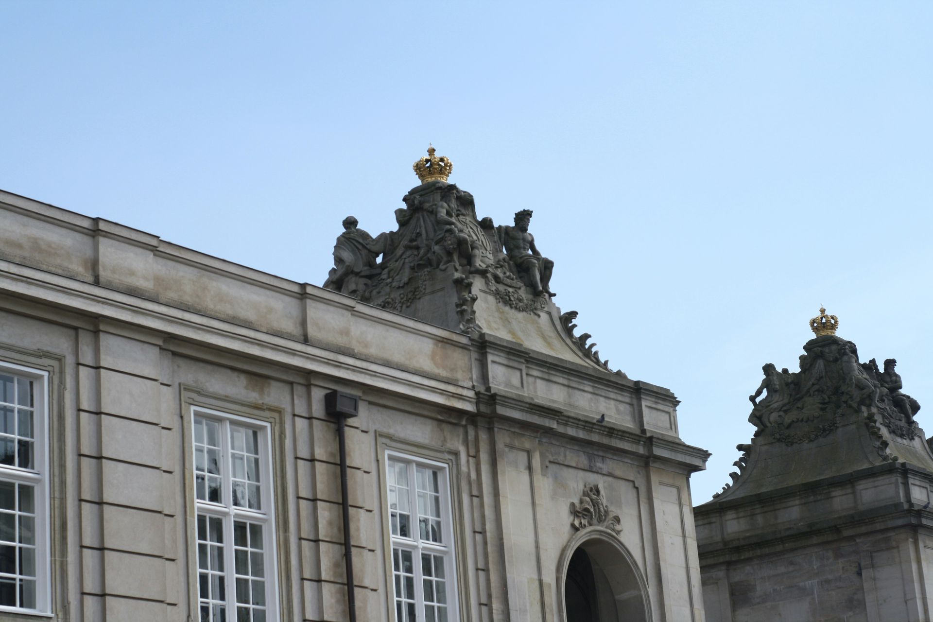 Gray stone building with ornate top and golden crown against a blue sky.