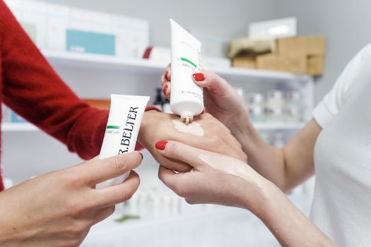 Woman testing a skincare cream on the back of her hand in a cosmetics store