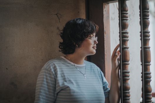 Side profile of a woman in her forties looking out a bright window