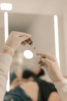 Doctor preparing an injectable collagen stimulator in a syringe at a clinic