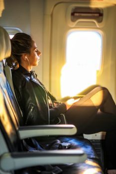 A woman relaxing in an airplane window seat with a neck pillow