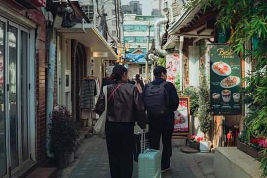 A traveler with a small suitcase walking along a Seoul street